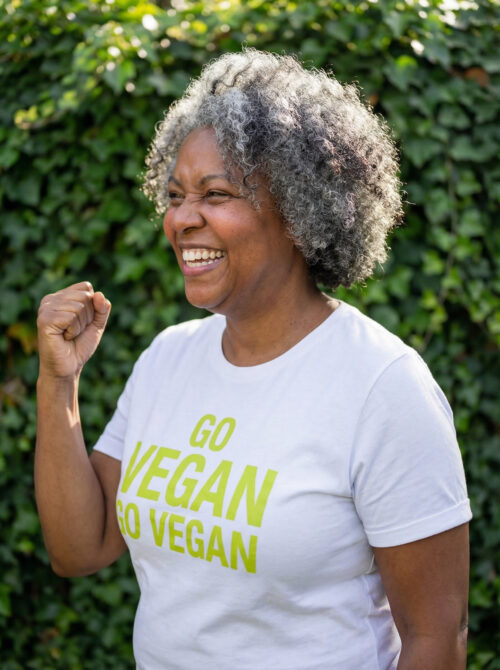 Happy mature African American woman in Go Vegan t-shirt celebrating outdoors with clenched fist